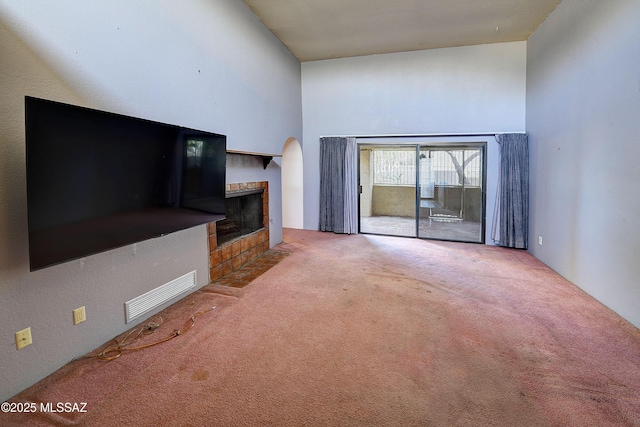 810 E Placita Leslie, Tucson, AZ 85718 - unfurnished living room with a tile fireplace, visible vents, carpet, and a towering ceiling