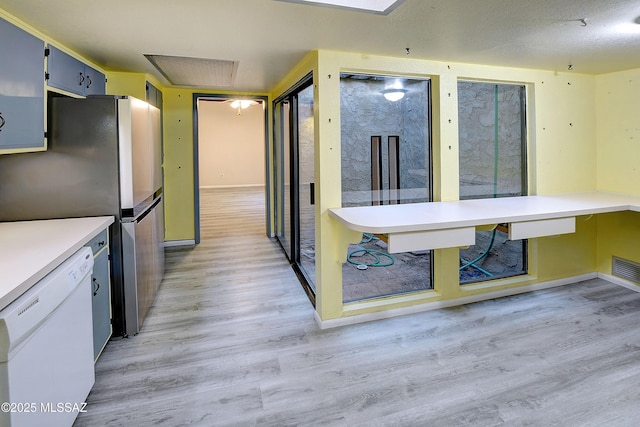 810 E Placita Leslie, Tucson, AZ 85718 - kitchen with freestanding refrigerator, light wood-type flooring, light countertops, white dishwasher, and baseboards