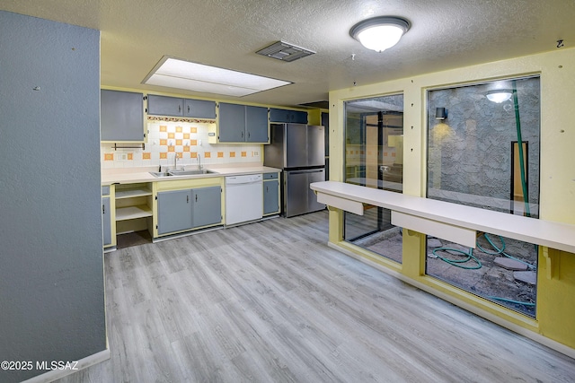 810 E Placita Leslie, Tucson, AZ 85718 - kitchen featuring a sink, freestanding refrigerator, a textured ceiling, light wood-style floors, and white dishwasher