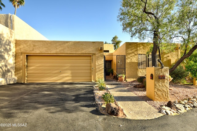 810 E Placita Leslie, Tucson, AZ 85718 - pueblo-style home with a gate, aphalt driveway, a garage, and stucco siding