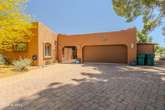 149 E Los Arcos, Green Valley, AZ 85614 - pueblo-style house featuring a garage, stucco siding, and driveway