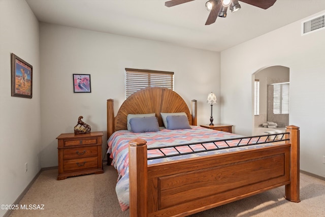 bedroom featuring light carpet, arched walkways, baseboards, and ceiling fan