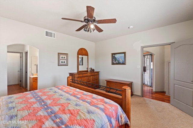 bedroom with arched walkways, a ceiling fan, and light colored carpet
