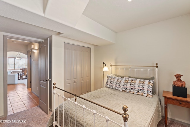 tiled bedroom with a closet, carpet flooring, and baseboards