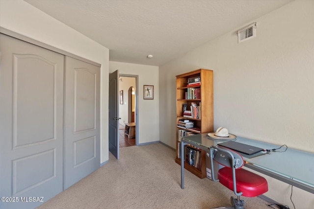carpeted office space with a textured ceiling and baseboards