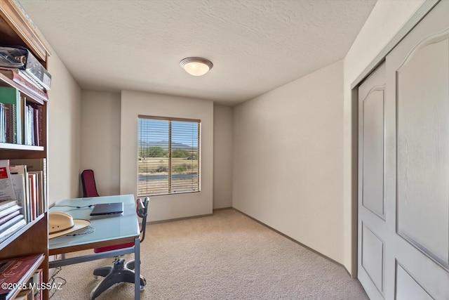 office space with light colored carpet, baseboards, and a textured ceiling