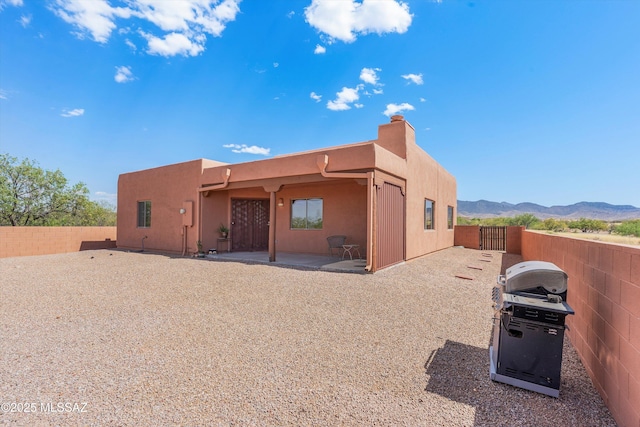 rear view of house with a mountain view, a fenced backyard, a patio, and stucco siding