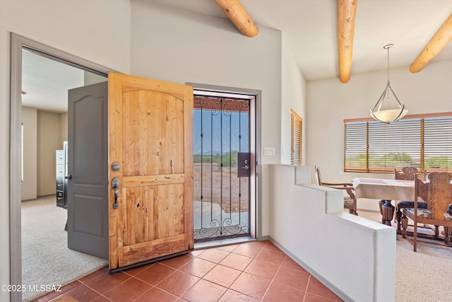 carpeted foyer featuring beam ceiling and tile patterned flooring