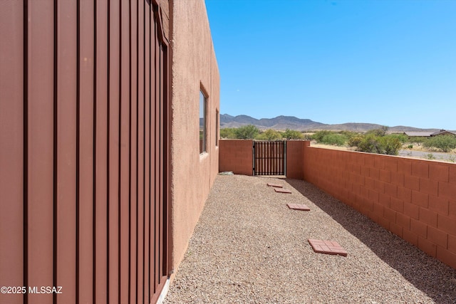 view of home's exterior featuring fence, a mountain view, a gate, and stucco siding