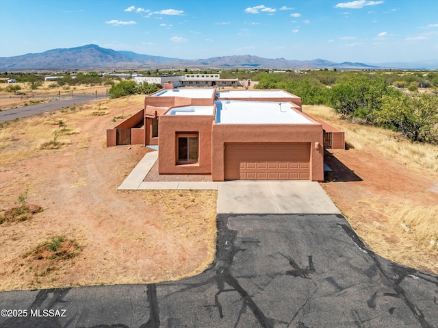 adobe home featuring a garage, driveway, stucco siding, and a mountain view