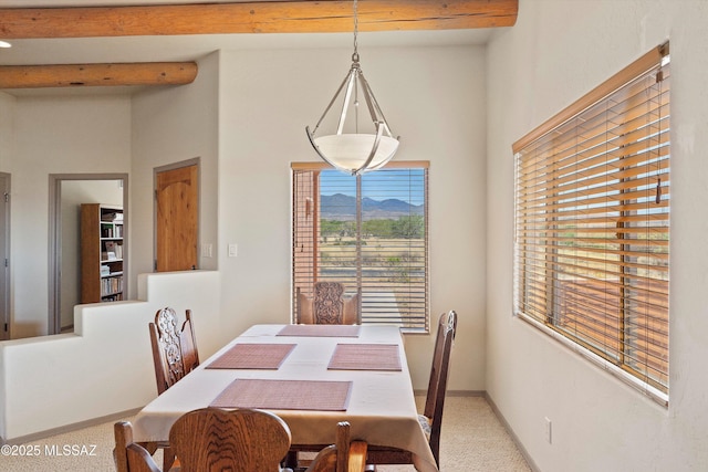 carpeted dining space featuring beamed ceiling, baseboards, and a mountain view