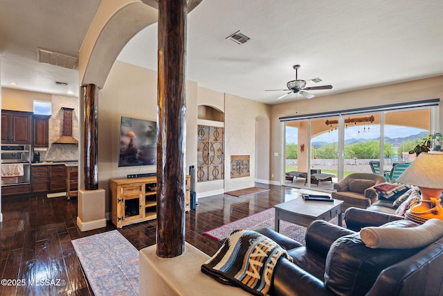 33 Camino Olympia, Rio Rico, AZ 85648 - living area with ornate columns, arched walkways, dark wood-style flooring, baseboards, and a ceiling fan