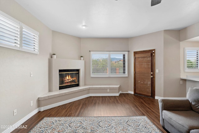11846 N Copper Butte Dr, Oro Valley, AZ 85737 - unfurnished living room featuring wood finished floors, plenty of natural light, a tile fireplace, and baseboards