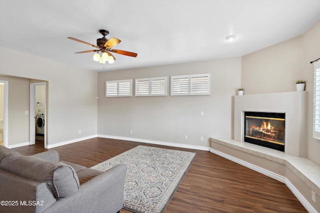11846 N Copper Butte Dr, Oro Valley, AZ 85737 - living room with ceiling fan, dark wood-style floors, a glass covered fireplace, washer / clothes dryer, and healthy amount of natural light
