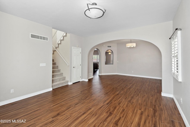 11846 N Copper Butte Dr, Oro Valley, AZ 85737 - unfurnished living room featuring arched walkways, wood finished floors, stairs, and baseboards