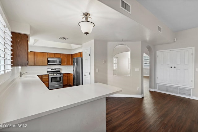 11846 N Copper Butte Dr, Oro Valley, AZ 85737 - kitchen featuring stainless steel appliances, a sink, brown cabinetry, light countertops, and dark wood-style flooring