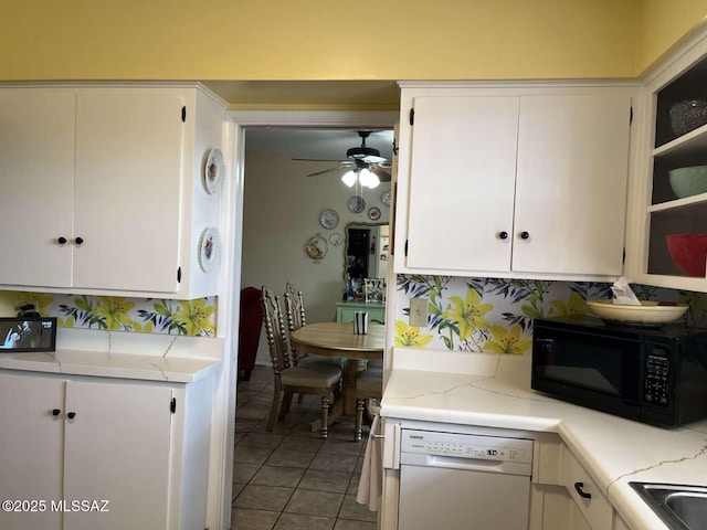 kitchen featuring black microwave, white cabinets, light tile patterned flooring, and dishwasher