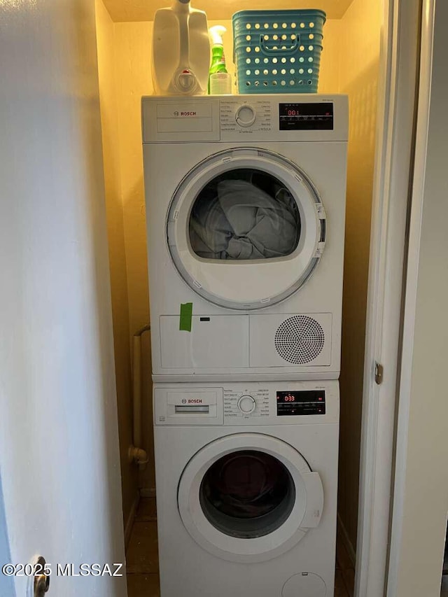 washroom featuring baseboards, laundry area, and stacked washer / drying machine