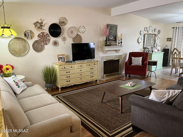 living room with beamed ceiling, a tile fireplace, and wood finished floors