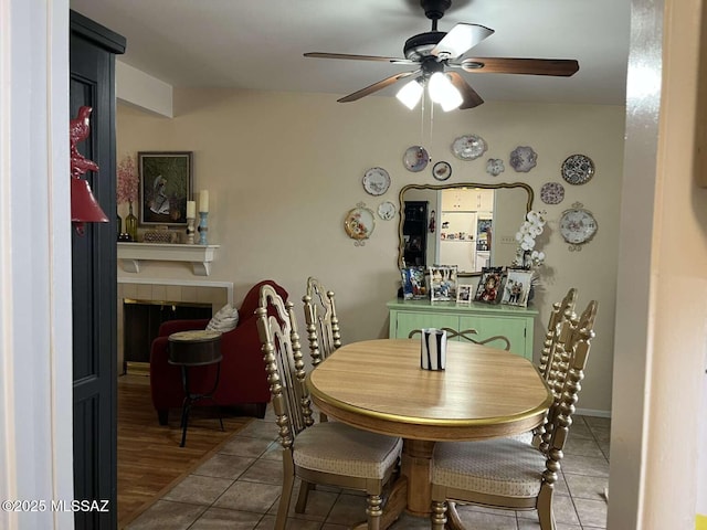 dining area with a fireplace, ceiling fan, and tile patterned floors