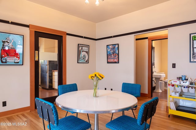 dining room featuring light wood-style flooring and baseboards