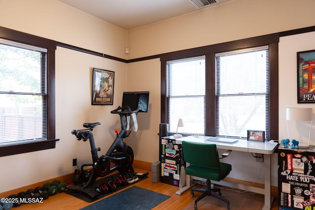 office space with healthy amount of natural light, wood finished floors, and baseboards