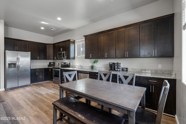 156 E Stone Ct, Tucson, AZ 85705 - kitchen featuring appliances with stainless steel finishes, dark brown cabinetry, light stone counters, a sink, and recessed lighting