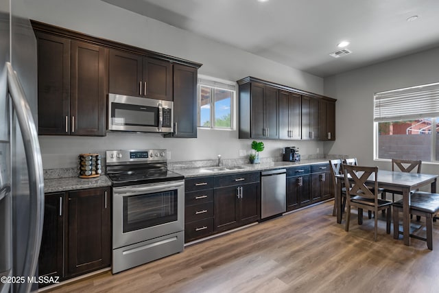 156 E Stone Ct, Tucson, AZ 85705 - kitchen featuring appliances with stainless steel finishes, a sink, light wood-style floors, and dark brown cabinetry