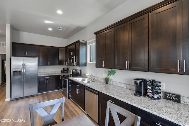 156 E Stone Ct, Tucson, AZ 85705 - kitchen with stainless steel appliances, a sink, light wood-style flooring, light stone counters, and dark brown cabinetry