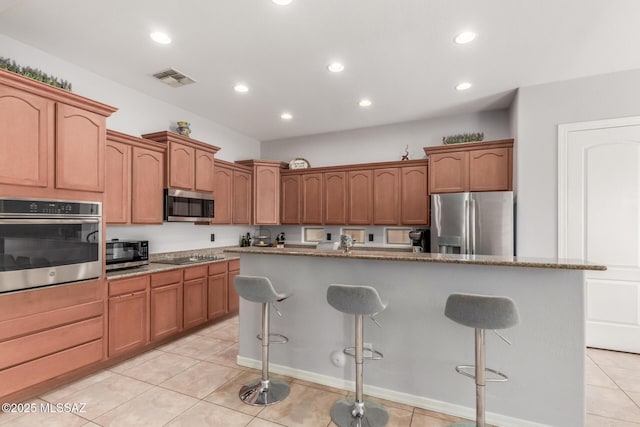 1933 E Lafayette Ave, Gilbert, AZ 85298 - kitchen with stone counters, light tile patterned floors, a kitchen bar, stainless steel appliances, and visible vents