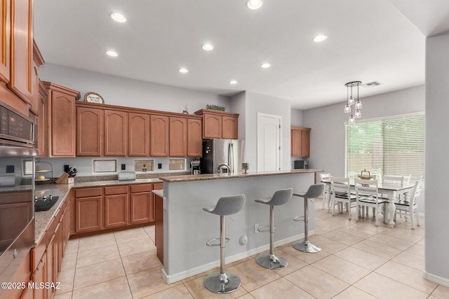 1933 E Lafayette Ave, Gilbert, AZ 85298 - kitchen with brown cabinets, an island with sink, a kitchen breakfast bar, visible vents, and appliances with stainless steel finishes