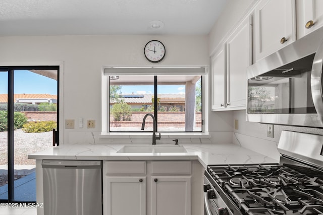 kitchen featuring white cabinetry, a wealth of natural light, stainless steel appliances, and a sink
