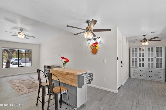 dining area with baseboards, light wood-style flooring, a ceiling fan, and visible vents