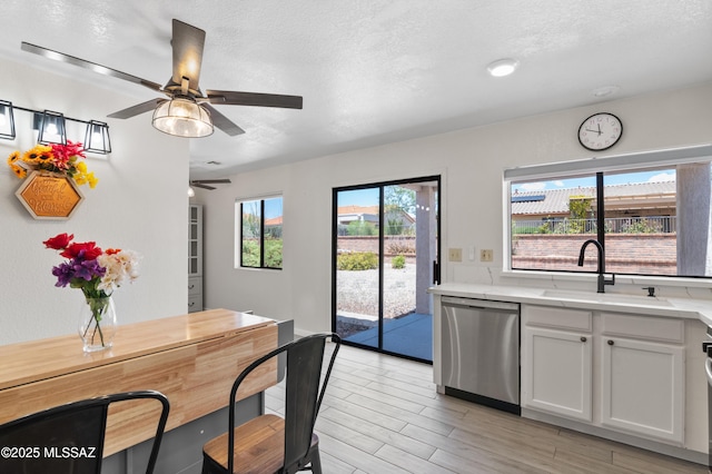 kitchen featuring dishwasher, ceiling fan, a sink, white cabinetry, and light wood-type flooring