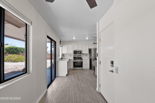 hallway featuring baseboards, light wood-style floors, and a sink