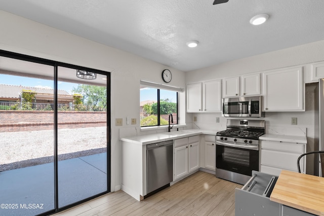 kitchen with white cabinetry, stainless steel appliances, light wood-type flooring, and a sink