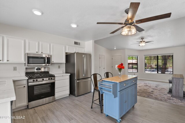 kitchen featuring blue cabinets, white cabinets, visible vents, and appliances with stainless steel finishes