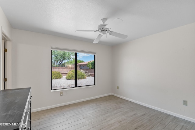 spare room featuring ceiling fan, baseboards, and light wood-style floors