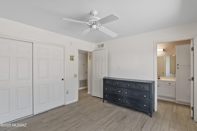 unfurnished bedroom featuring light wood finished floors, a closet, ensuite bath, and visible vents
