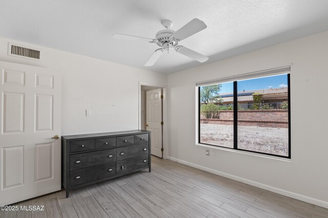 unfurnished bedroom featuring light wood finished floors, visible vents, baseboards, and ceiling fan