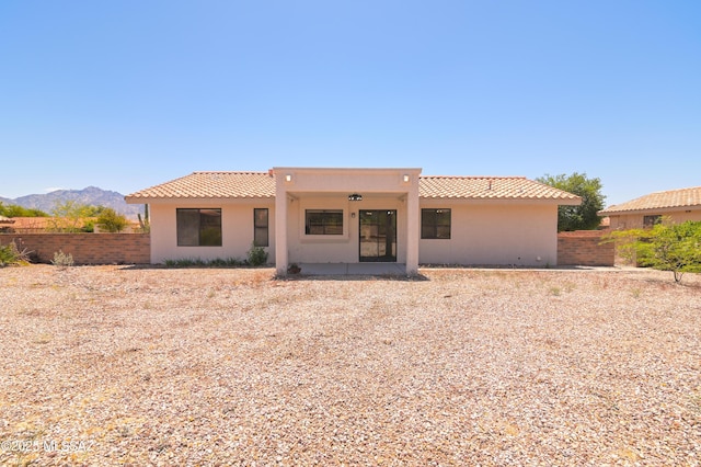 rear view of house with a tile roof, fence, stucco siding, and a mountain view