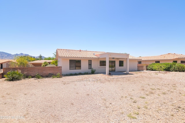 back of house featuring stucco siding, a tiled roof, a mountain view, and fence