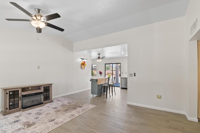 living area with baseboards, ceiling fan, visible vents, and vaulted ceiling