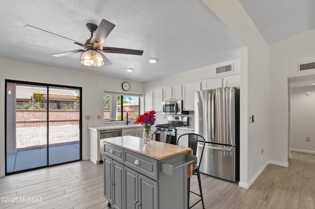 kitchen with white cabinets, gray cabinetry, stainless steel appliances, and visible vents