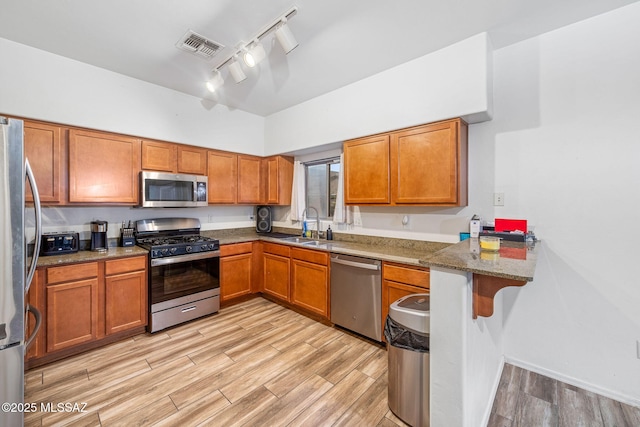 442 E Placita Cordel, Sahuarita, AZ 85629 - kitchen with stainless steel appliances, track lighting, light wood-style floors, brown cabinets, and a sink