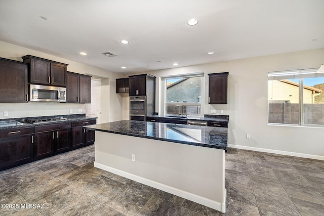 8695 W Cadwell Way, Marana, AZ 85653 - kitchen with stainless steel appliances, a sink, dark stone countertops, dark brown cabinets, and baseboards