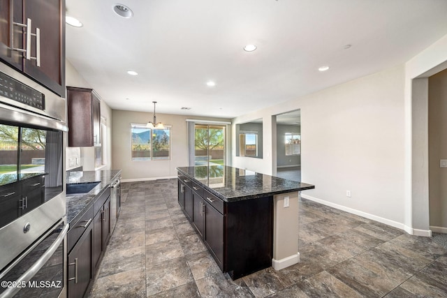8695 W Cadwell Way, Marana, AZ 85653 - kitchen with baseboards, dark stone countertops, a center island, a chandelier, and dark brown cabinetry