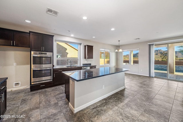 8695 W Cadwell Way, Marana, AZ 85653 - kitchen with appliances with stainless steel finishes, a sink, baseboards, dark brown cabinetry, and a kitchen island