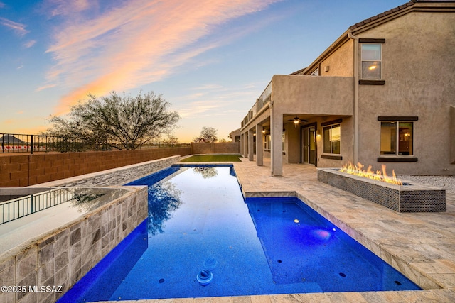 8695 W Cadwell Way, Marana, AZ 85653 - pool at dusk with an outdoor fire pit, a fenced backyard, a patio area, and a ceiling fan