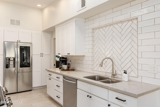 kitchen with stainless steel appliances, tasteful backsplash, visible vents, and a sink